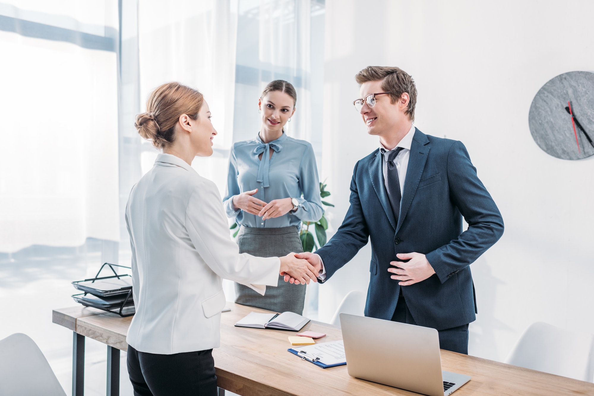 cheerful-recruiter-shaking-hands-with-woman-near-colleague-in-office.jpg